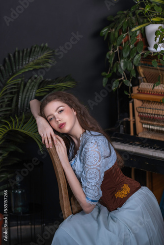 Brunette girl in a blue dress sits on a vintage chair