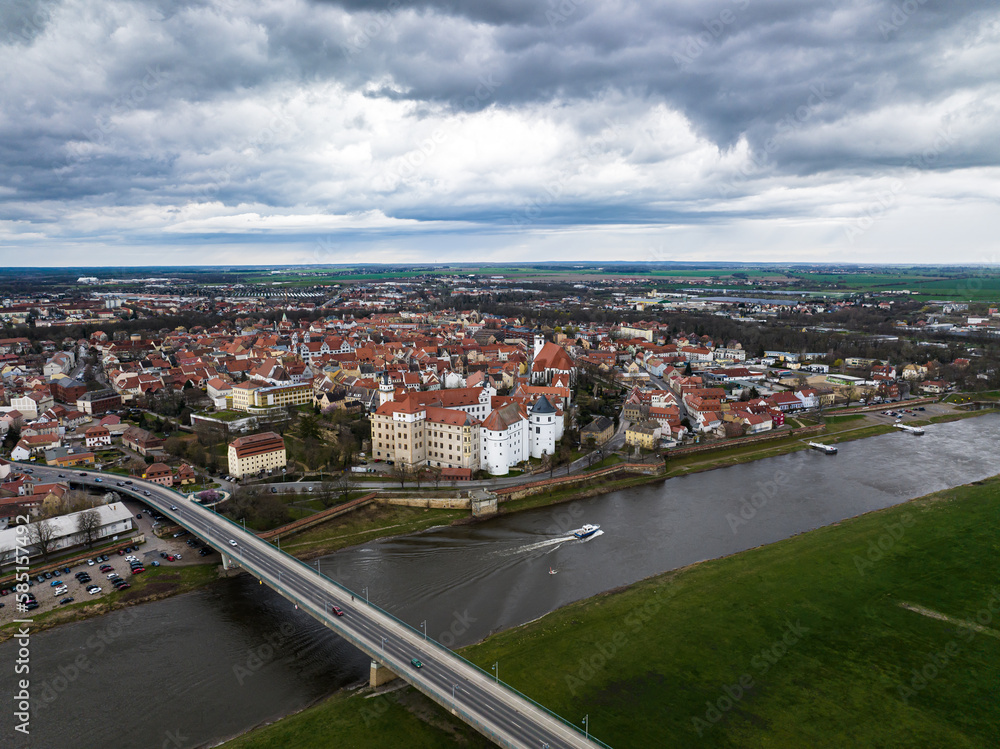 torgau with a cloudy sky. rain clouds over the city. river elbe and elbe bridge in the foreground. old town and surroundings in the background