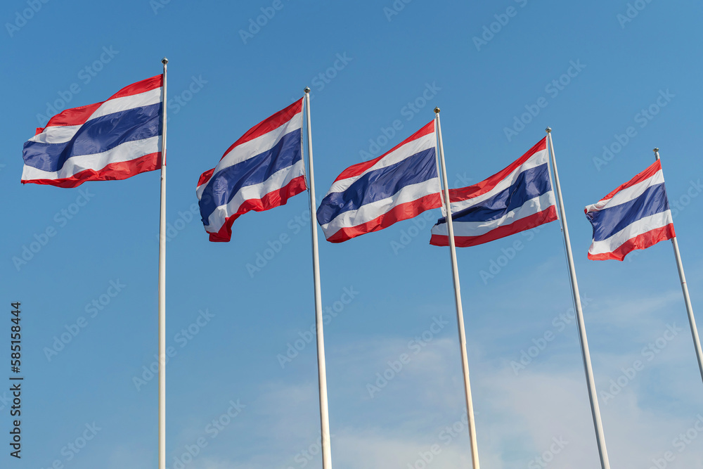 The national flags of Thailand flutter against a blue sky. The national flags of Thailand flutter against a blue sky.