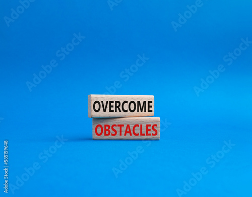 Overcome obstacles symbol. Concept words Overcome obstacles on wooden blocks. Beautiful blue background. Business and Overcome obstacles concept. Copy space.