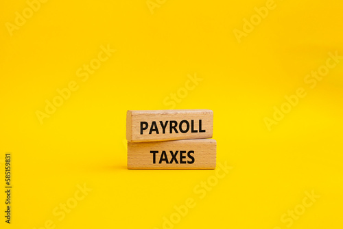 Payroll taxes symbol. Concept word Payroll taxes on wooden blocks. Beautiful yellow background. Businessman hand. Business and Payroll taxes concept. Copy space