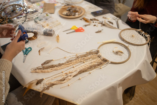 creativity, a dream catcher made of threads, feathers lies on the table, in the workshop. Master class, diligence, accuracy, hobby
