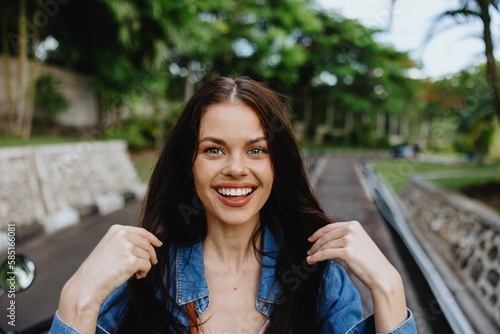 Portrait of a woman brunette smile with teeth walking outside against a backdrop of palm trees in the tropics, summer vacations and outdoor recreation, the carefree lifestyle of a freelance student.