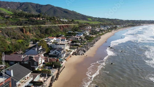 2023 - Excellent aerial footage pulling away from waves hitting the shore outside beach houses at Point Mugu, California. photo