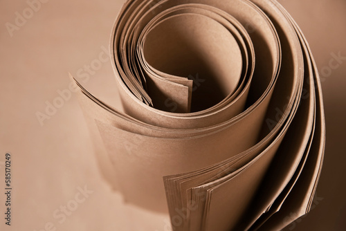 Roll of brown kraft paper for packaging various products, production of ecological bags, top view, selective focus