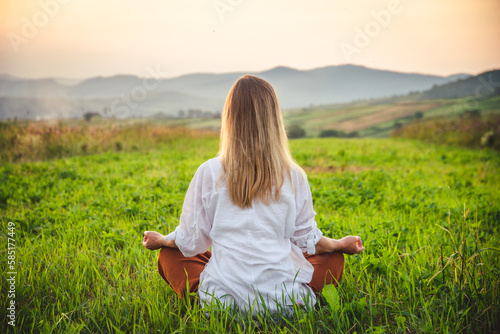 Woman doing yoga on the green grass at the mountain. Carpathians