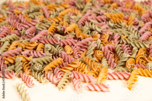 Rice vegetable pasta in the form of spirals on a white background. Healthy rice pasta with tomatoes  selenera  carrots and beets
