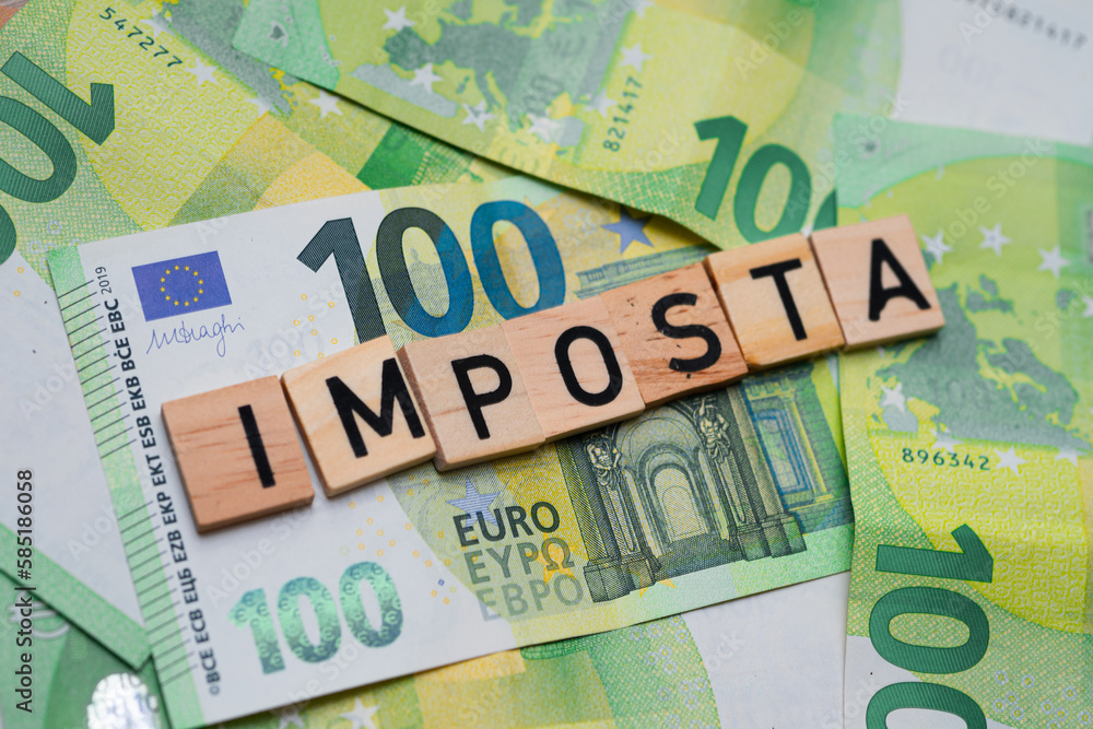 inscription Imposta which means tax in Italian next to euro banknotes. Concept showing the Italian economy inscription Imposta which means tax in Italian next to euro banknotes. Concept showing the Italian economy
