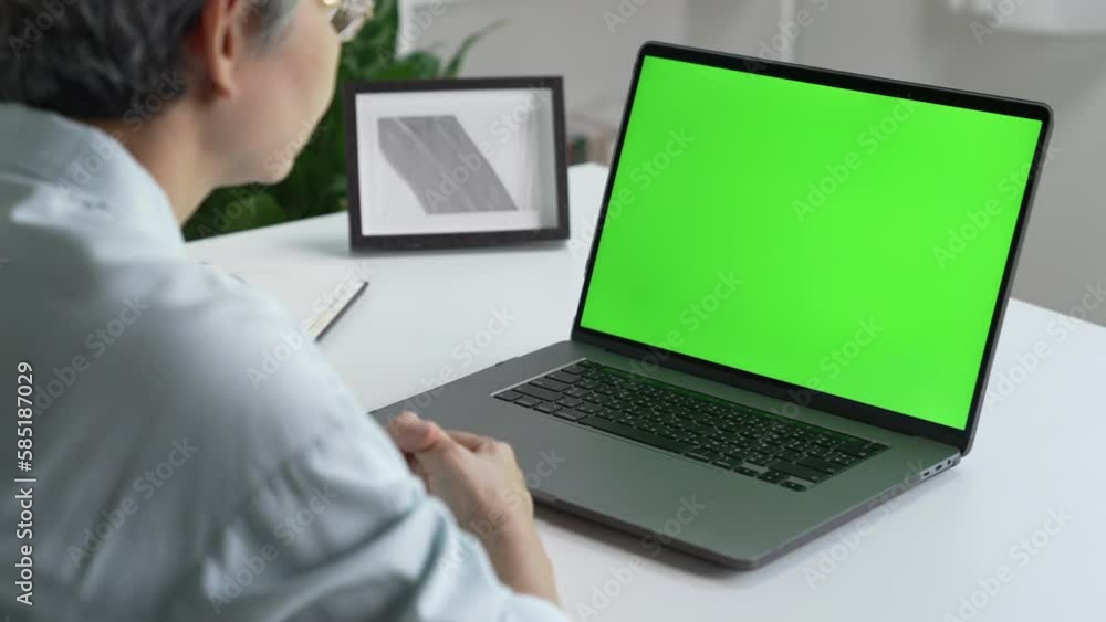 Mature Asian woman using laptop with green screen Mature Asian woman using laptop with green screen