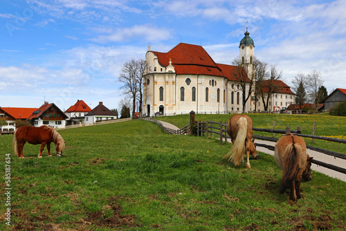 Die berühmte Wieskirche bei Steingaden in Bayern mit drei Pferden im Vordergrund