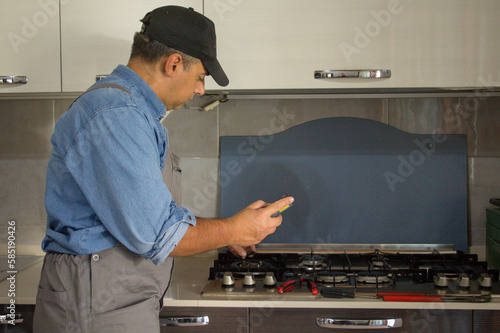 Image of a handyman technician who with a detector carries out checks in a kitchen for safety and gas leaks from the stove. Prevention and safety at home.
