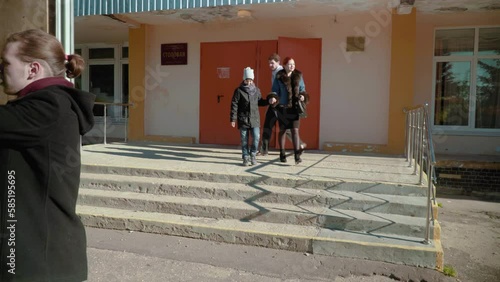 mom dad and son leave school, while movers load the car