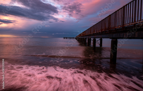 Seascape with dramatic colourful sunset in the ocean. Footpath bridge pier in the sea
