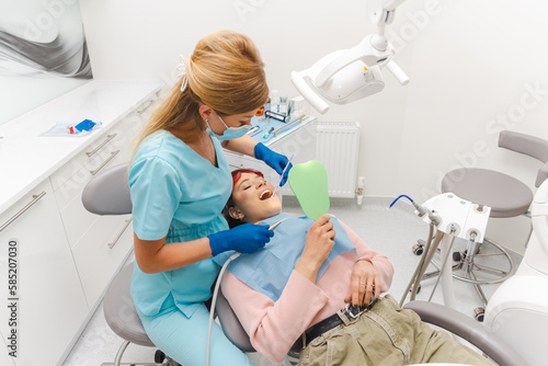 Young woman is lying on the dentist chair and is getting some teeth done.