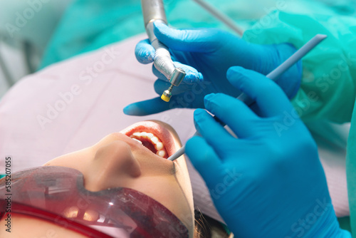 Close up shot of a young woman with her mouth open at the dentist in gloves.