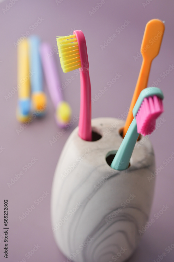  colorful toothbrushes in white mug against a wall 