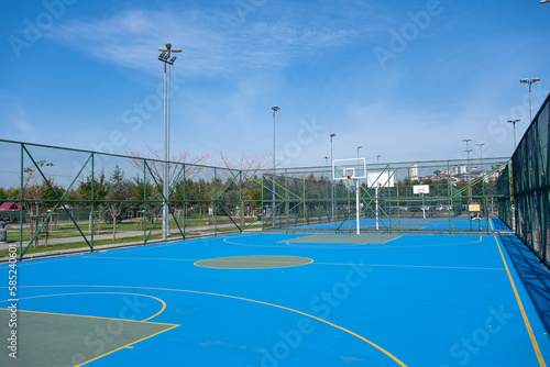 Basketball court in park. Outdoor basketball field with nobody, blue surface, summer, sunny day
