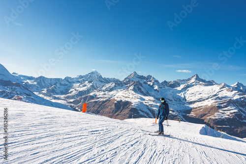 Young man skiing in Zermatt ski resort right next to the famous Matterhorn peak. Beautiful sunny day for snowboarding. Winter sports concept. © Aerial Film Studio