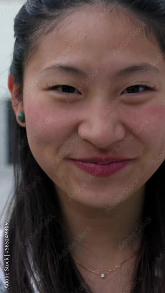Vertical front view portrait of young asian cheerful woman looking and smiling at camera while walking in city street. Happy joyful people concept Vertical front view portrait of young asian cheerful woman looking and smiling at camera while walking in city street. Happy joyful people concept