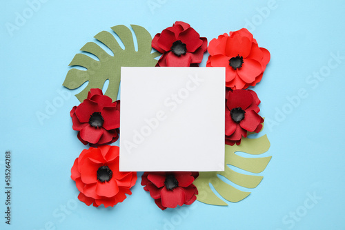 Blank paper sheet with poppy flowers and palm leaves on blue background