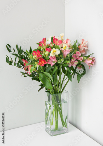 Glass vase with bouquet of beautiful alstroemeria flowers near light wall, closeup © Pixel-Shot