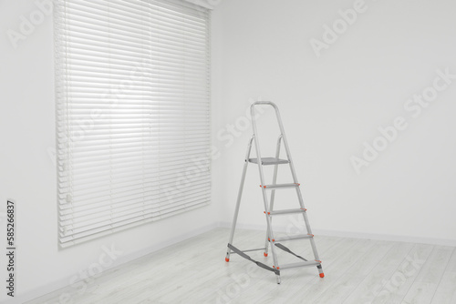 Metallic folding ladder indoors, space for text