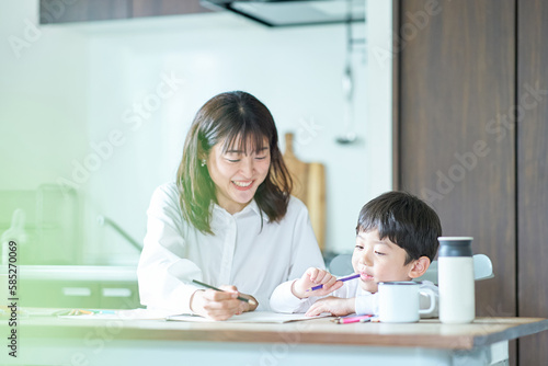 部屋で鉛筆とノートを使って勉強する親子