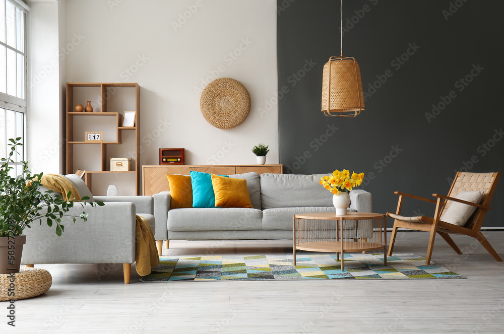Fototapeta premium Interior of stylish living room with cozy sofa, armchairs and flower vase on coffee table