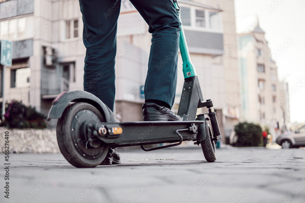 Obraz premium Unknown businessman in classic suit ride on electric mobile scooter. a businessman rents a scooter on the street of the city. Modern eco friendly transport. Fast speed driving electric transport
