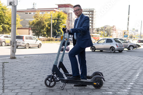 Young business man in a suit riding an electric scooter on business meeting. Ecological transportation concept. rent an electronic scooter on the city street. alternative commute