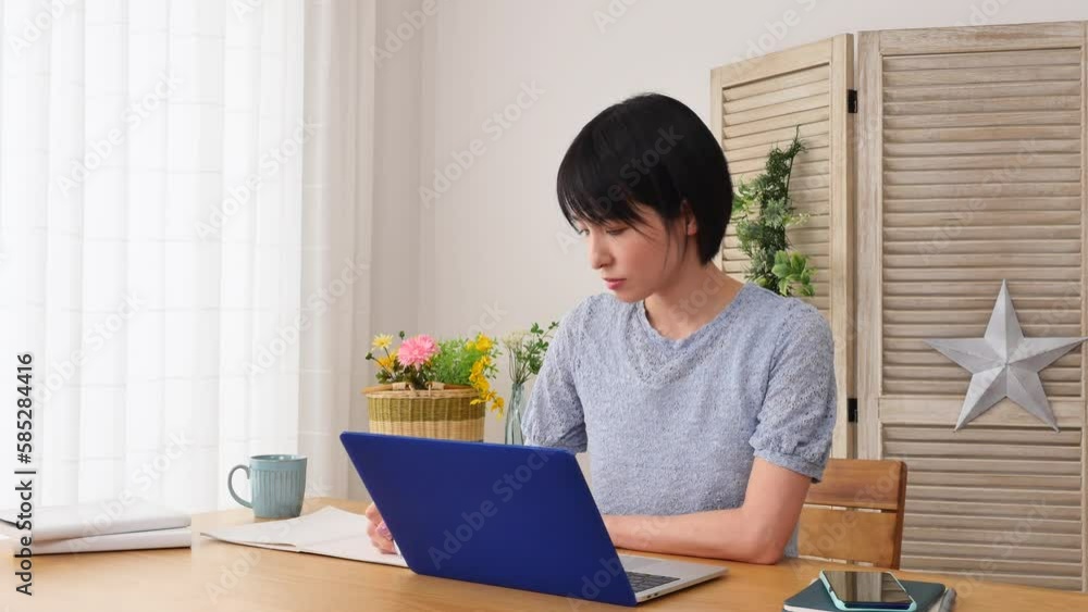 自宅でノートパソコンを使って勉強する女性 自宅でノートパソコンを使って勉強する女性