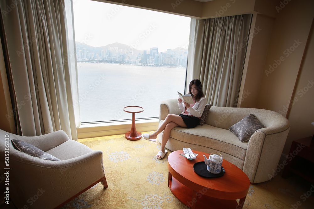 woman take a break and reading at home with Victoria harbour city view in Hong Kong