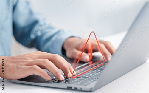 Developer using laptop with warning triangle sign for error notification and maintenance concept.