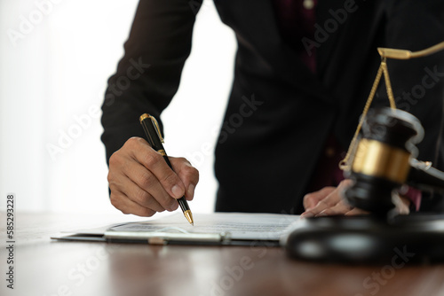 Female lawyer or legal counsel sitting at desk reading and reviewing data in file folder, legal book in accordance with the principles of jurisprudence to study and find information.