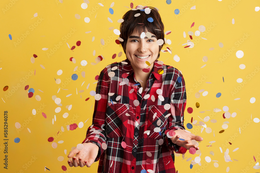 Happy androgynous person surrounded by flying confetti Happy androgynous person surrounded by flying confetti