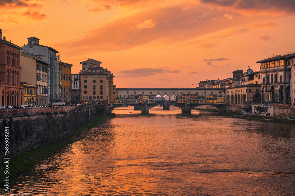 a beautiful orange sky hangs over a river in a european city