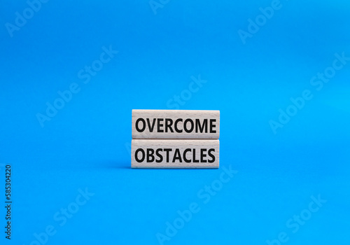 Overcome obstacles symbol. Concept words Overcome obstacles on wooden blocks. Beautiful blue background. Business and Overcome obstacles concept. Copy space.