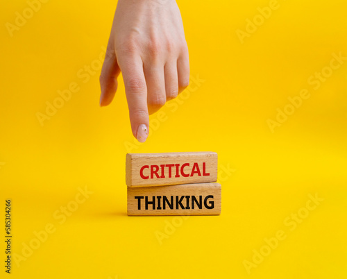 Critical thinking symbol. Wooden blocks with words Critical thinking. Businessman hand. Beautiful yellow background. Business and Critical thinking concept. Copy space.