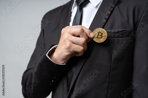 Closeup of business man wearing business suit showing golden Bitcoin cryptocurrency coin with copy space. Bitcoin cryptocurrency is new future online financial payment, transferring as digital money.