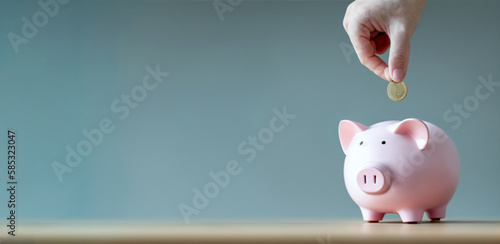 A piggy bank and a hand holding a coin. The image represents saving and inflation. Neutral background. Ideal as a banner or header. Space for text. Copy space and blank text. 