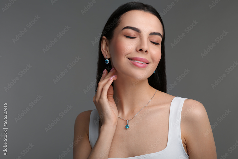 Beautiful young woman with elegant jewelry on dark grey background Beautiful young woman with elegant jewelry on dark grey background