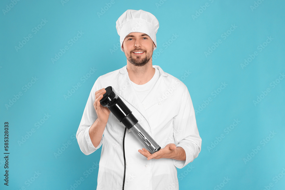 Smiling chef holding sous vide cooker on light blue background Smiling chef holding sous vide cooker on light blue background