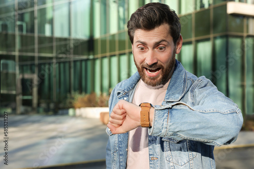Принти на полотні Emotional man checking time on watch near building