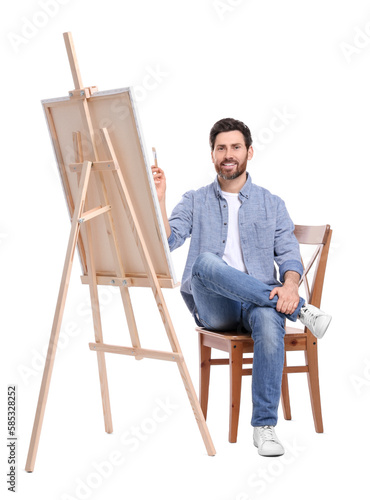 Happy man painting with brush against white background. Using easel to hold canvas