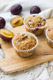 Seasonal muffins with plums and poppy seeds on white wooden and textile background close up selective focus 