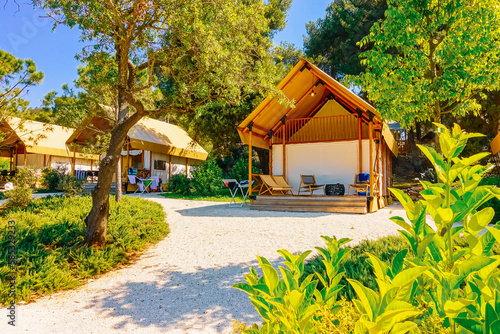 Gorgeous view of canvas glamping bell tents in a green wood on a sunny day. Croatia, Europe.