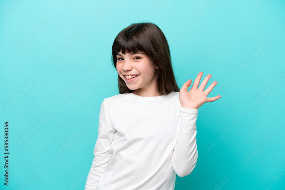 Fototapeta premium Little caucasian girl isolated on blue background saluting with hand with happy expression