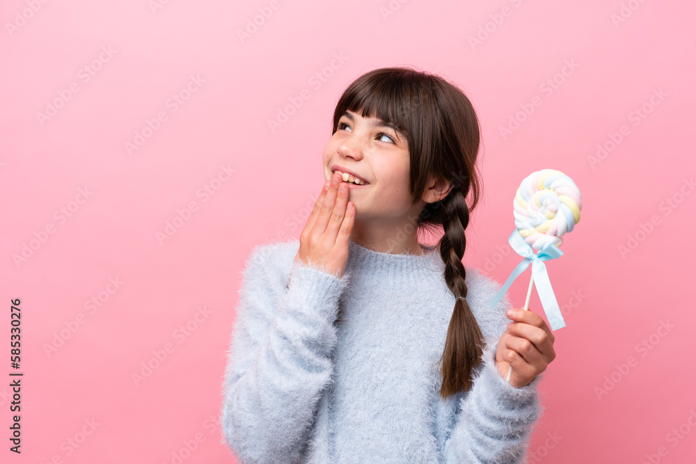 Little caucasian girl holding a lollipop looking up while smiling Little caucasian girl holding a lollipop looking up while smiling