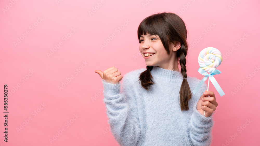 Little caucasian girl holding a lollipop pointing to the side to present a product Little caucasian girl holding a lollipop pointing to the side to present a product