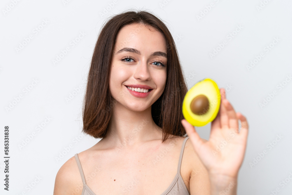 Young Ukrainian woman isolated on white background holding an avocado while smiling. Close up portrait Young Ukrainian woman isolated on white background holding an avocado while smiling. Close up portrait